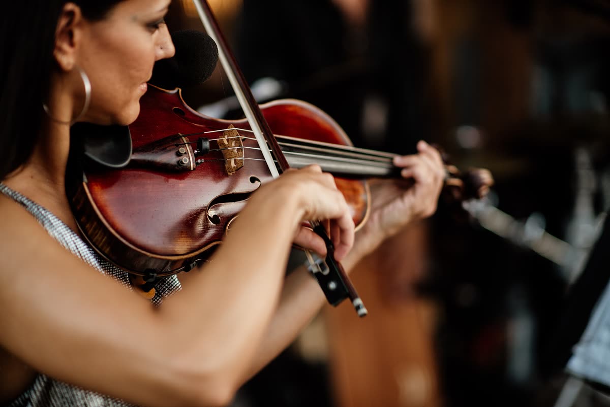 Primo piano di mani e arco su un violino